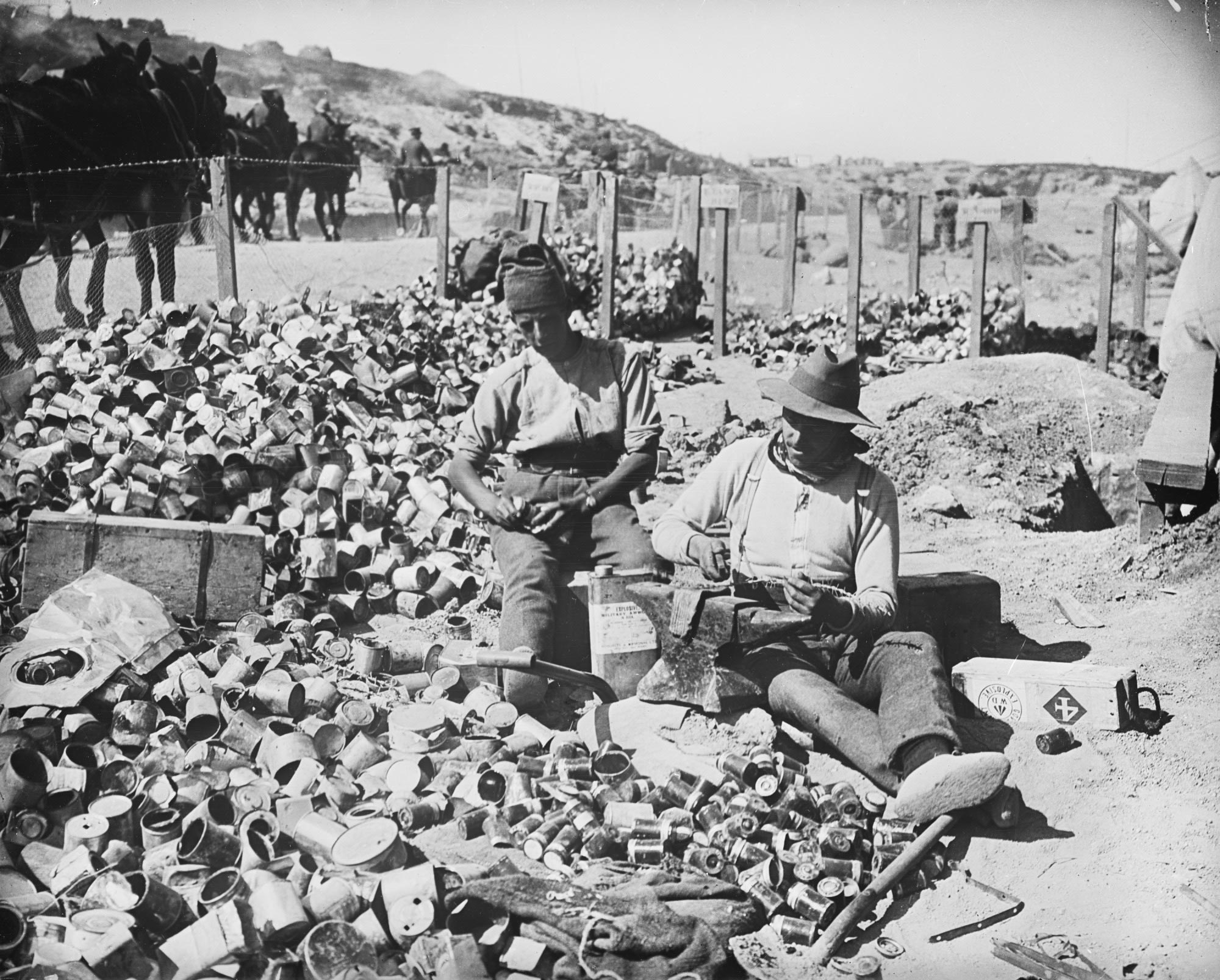 <p>Two soldiers cutting up barbed wire for jam tin bombs, Gallipoli, 1915</p>
