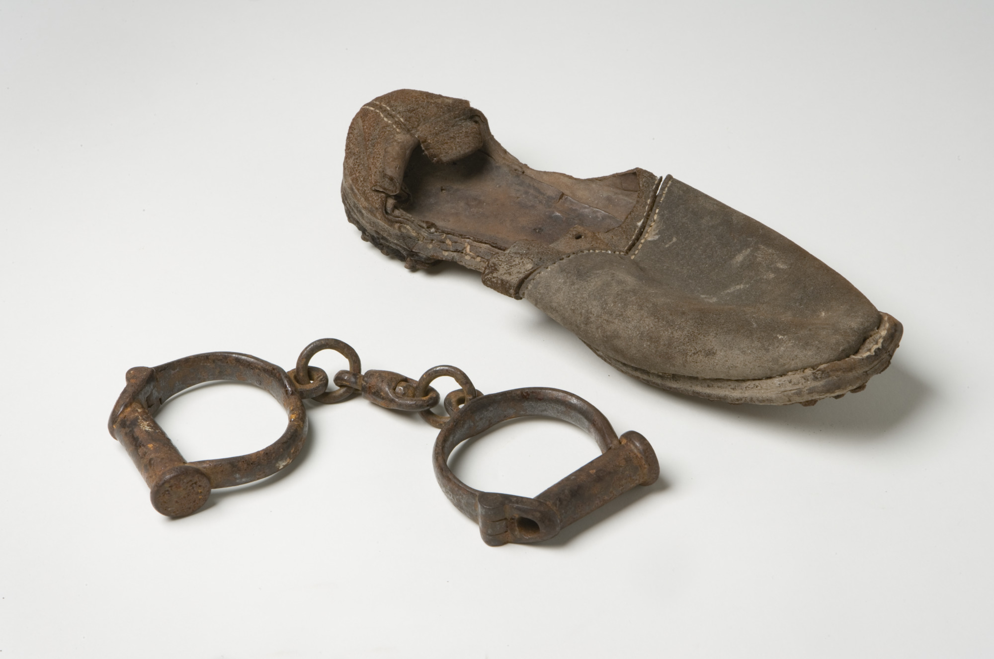 <p>Metal handcuffs and hand-stitched leather shoe</p>