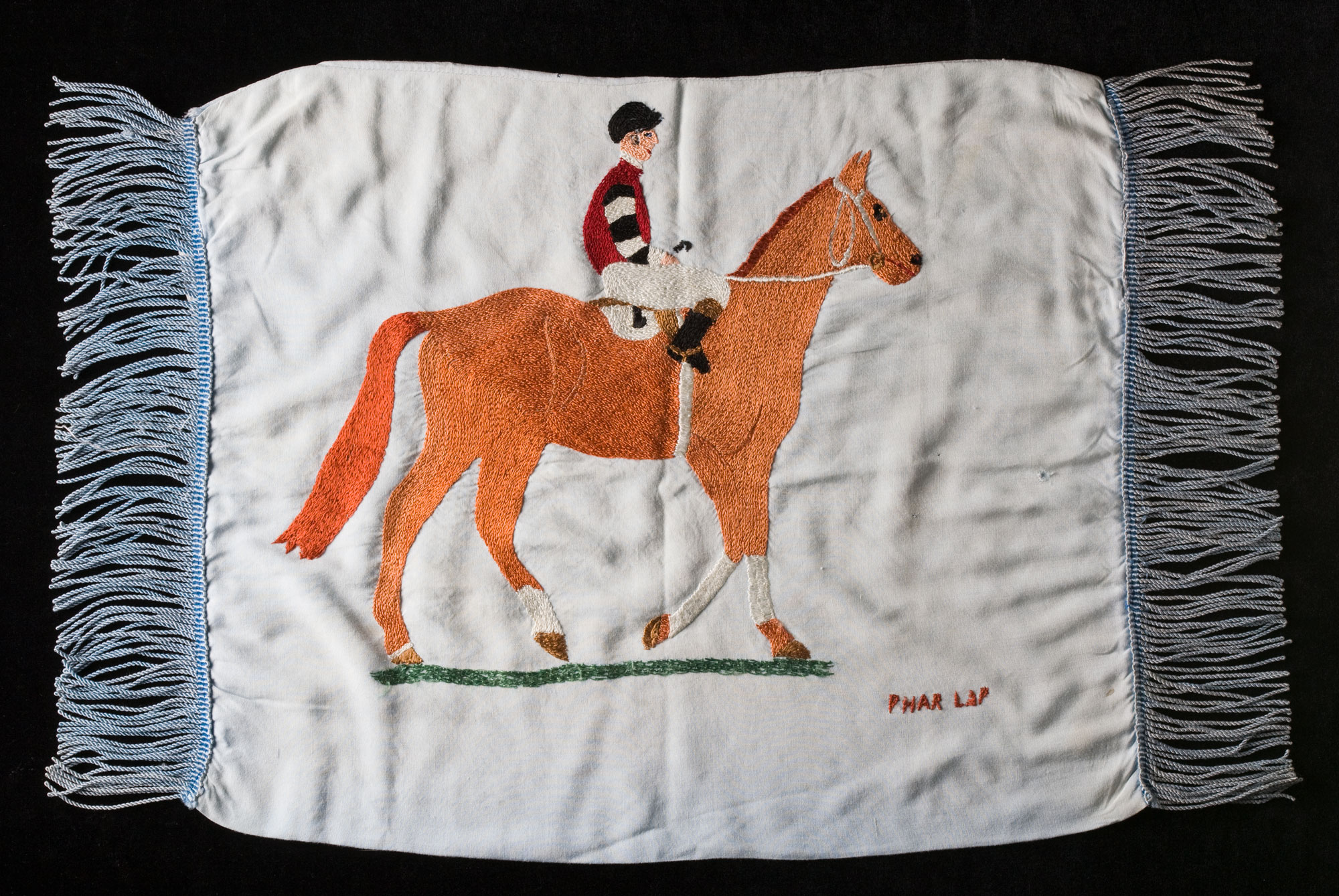 Cushion cover with hand embroidered image of Phar Lap and jockey.