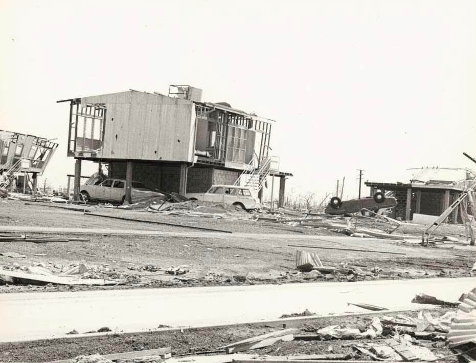 Black and white photograph of house ruins impacted by a cyclone.