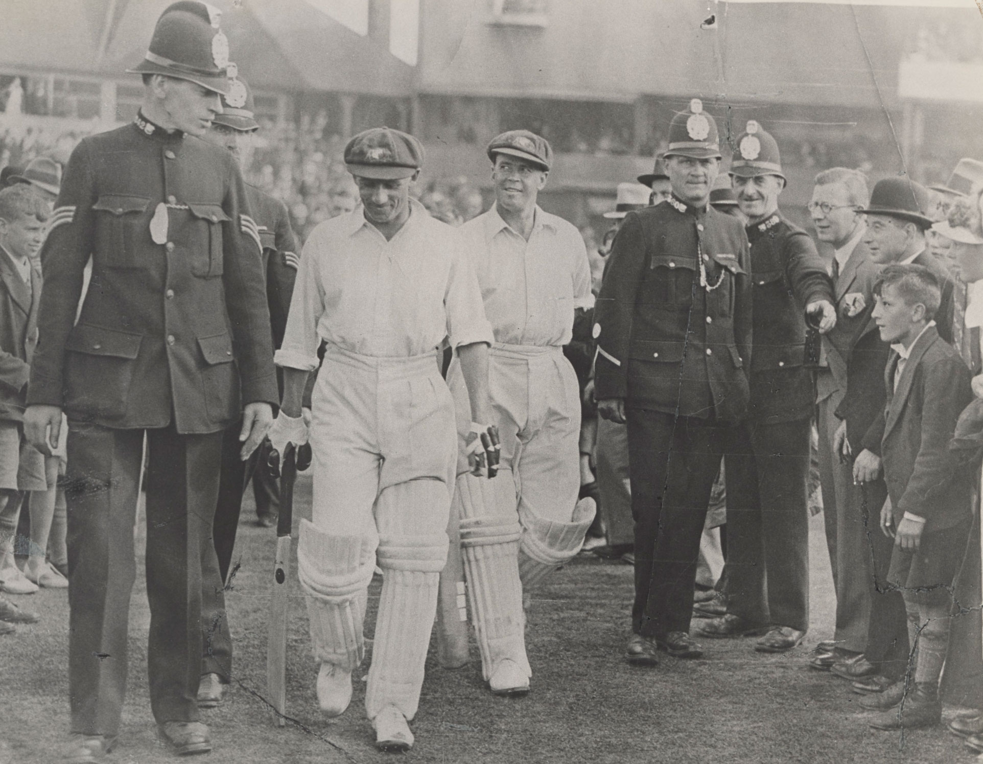 Australian batsmen Don Bradman and Bill Ponsford being escorted from the field by English police, 1934.