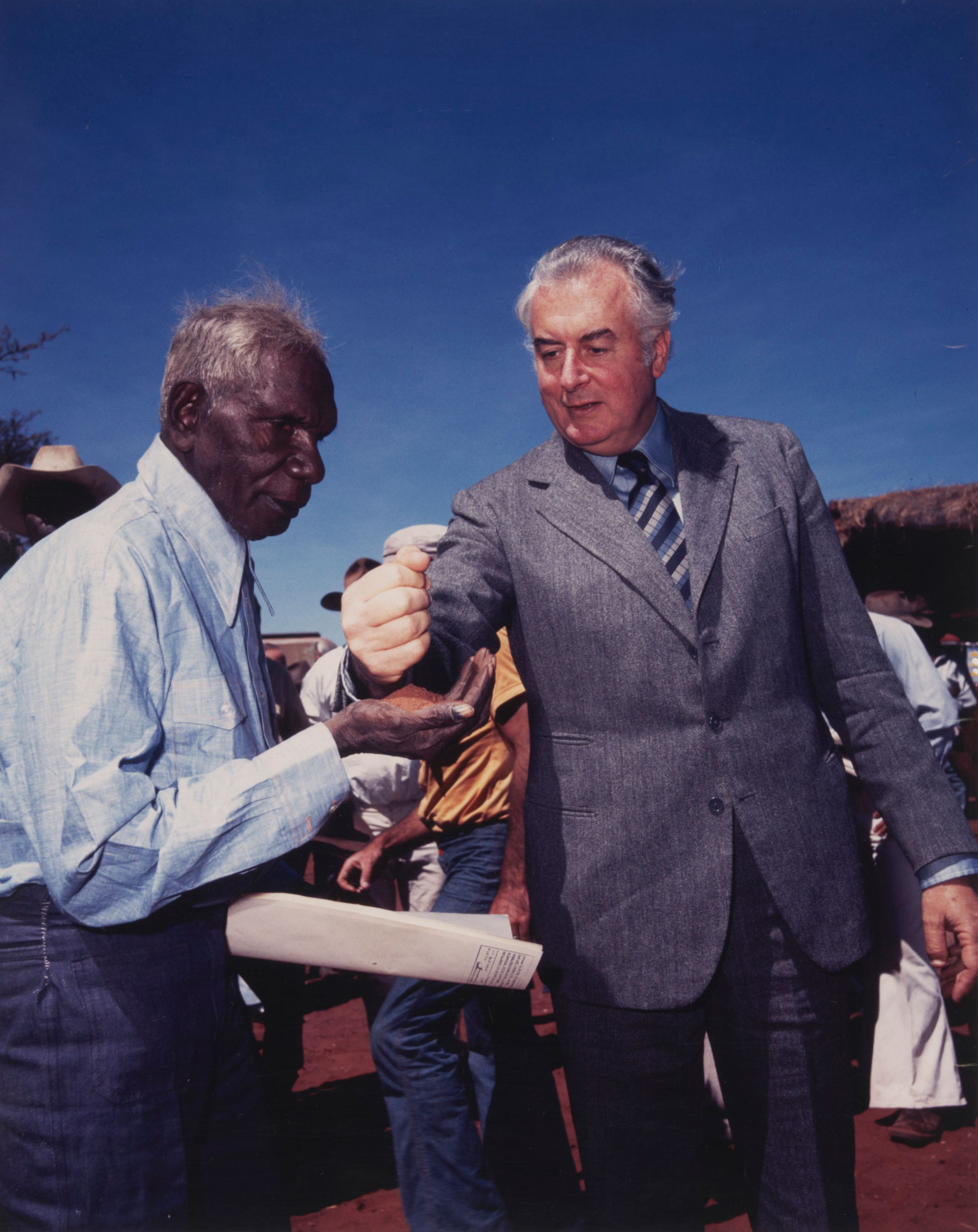 <p>Gough Whitlam pouring a handful of red soil into the hands of Vincent Lingiari, by Mervyn Bishop, 1975</p>
