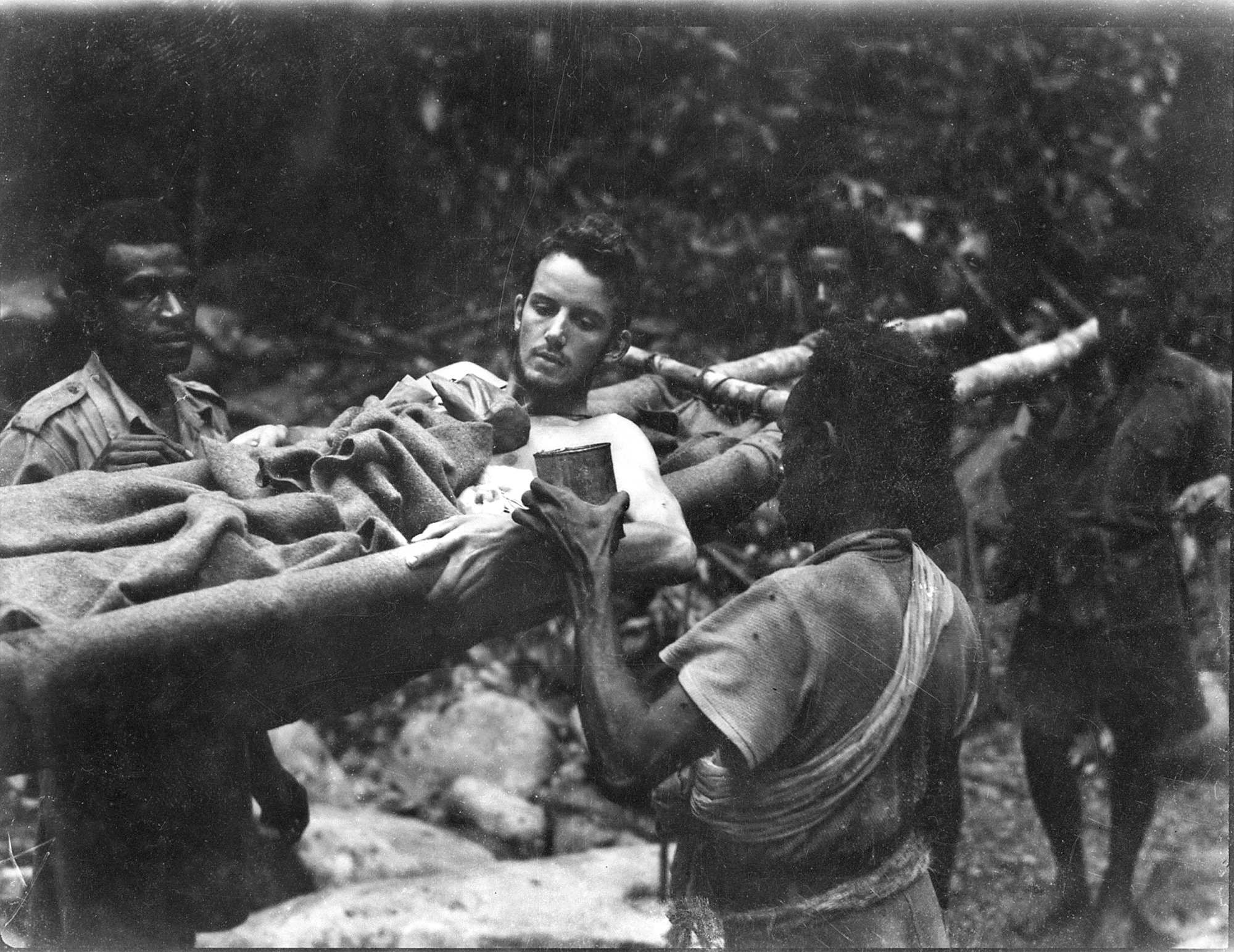 Papuan stretcher bearers help an injured Australian soldier on the Kokoda Trail, 1942.