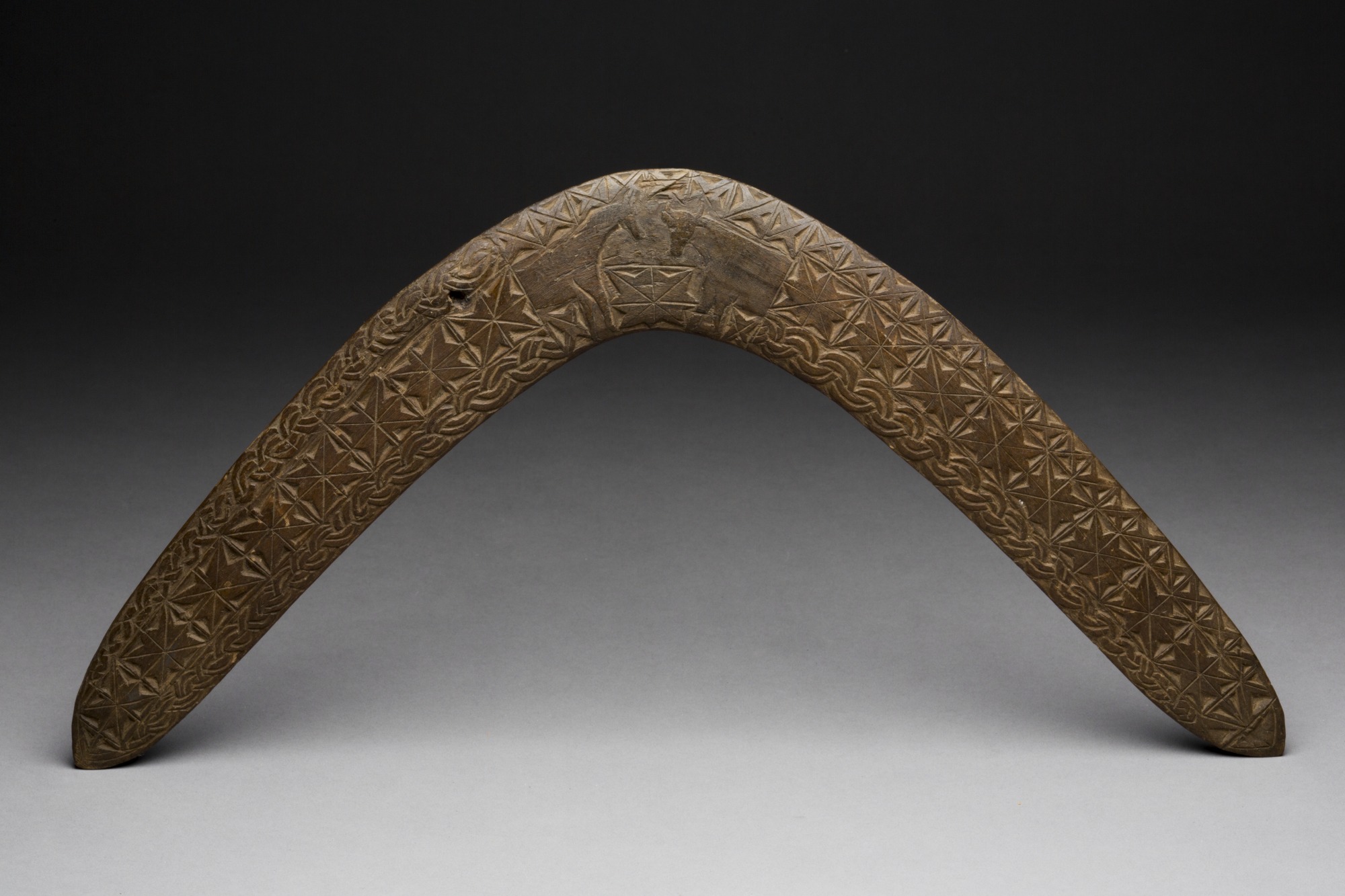 Boomerang with carving of horse and cow.