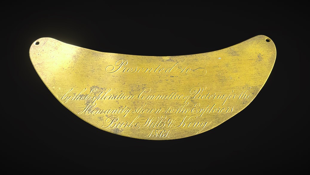 A shallow crescent-shaped brass breastplate with a hole at each corner, engraved with text that reads 'Presented to / [blank] / by the Exploration Committee of Victoria for the / Humanity shewn to the Explorers / Burke, Wills & King / 1861'.