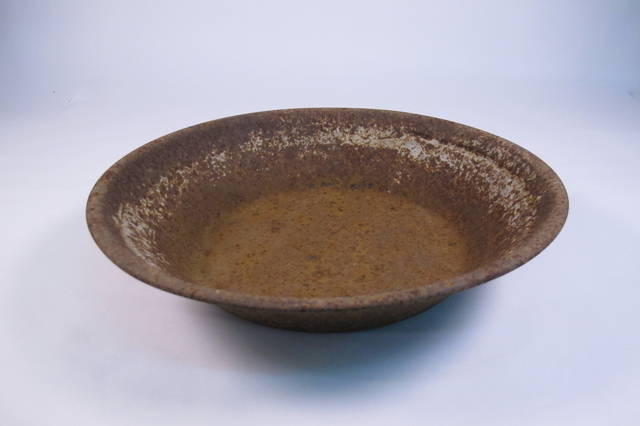 A brown coloured heavily rusted circular metal gold panning pan.