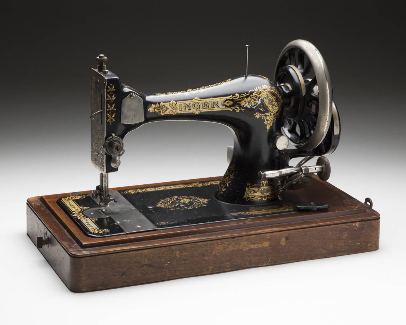 Hand-operated Singer sewing machine, black with gold floral motifs.