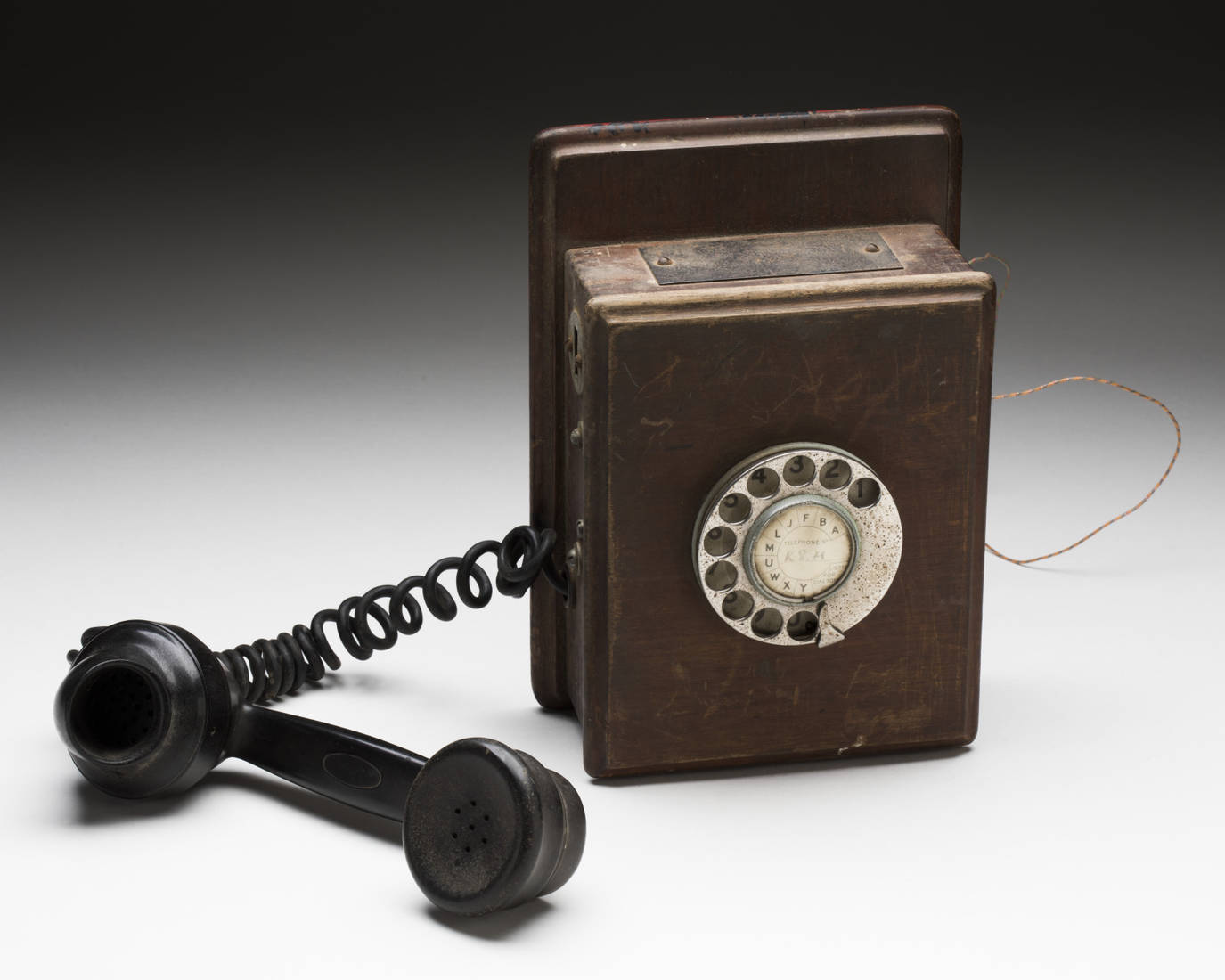Brown wooden wall telephone with a black plastic handset