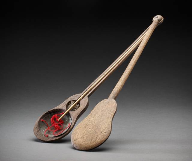 A set of brown coloured wooden banjo shaped Chinese scales. The scales consist of two identical hollowed shaped pieces of wood forming a base and lid. Inside there is a bone or ivory measuring rod with a metal weight and metal scoop with red twine attached.