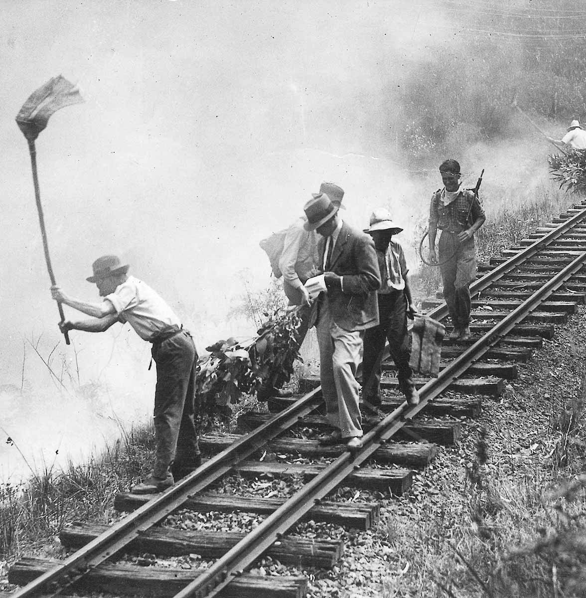 Black and white photograph of men along train tracks attempting to fight a fire.