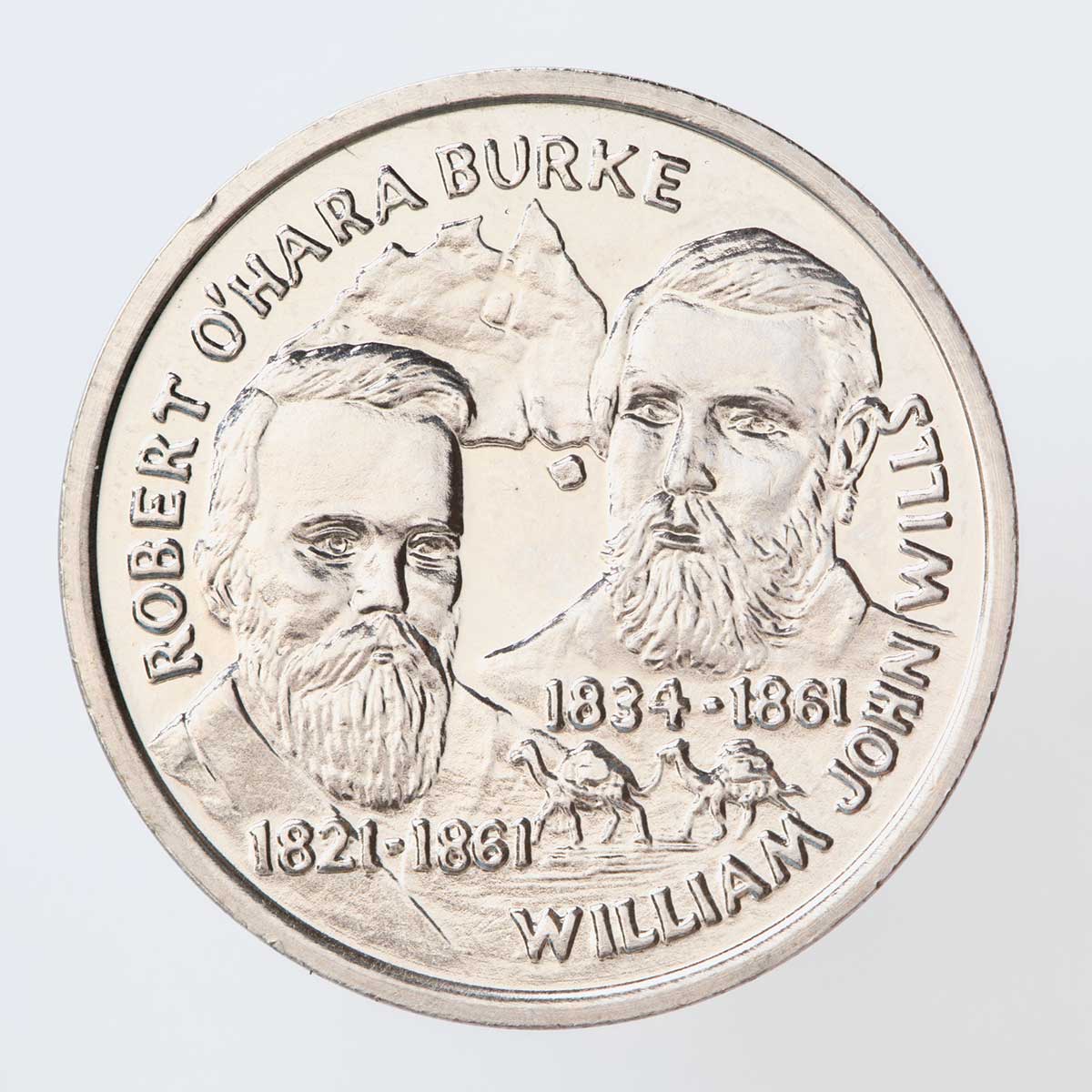 A silver coloured metal commemorative medal depicting the explorers Burke and Wills. The explorers are depicted on the front with their full names and dates written below with a small map of Australia in the background.
