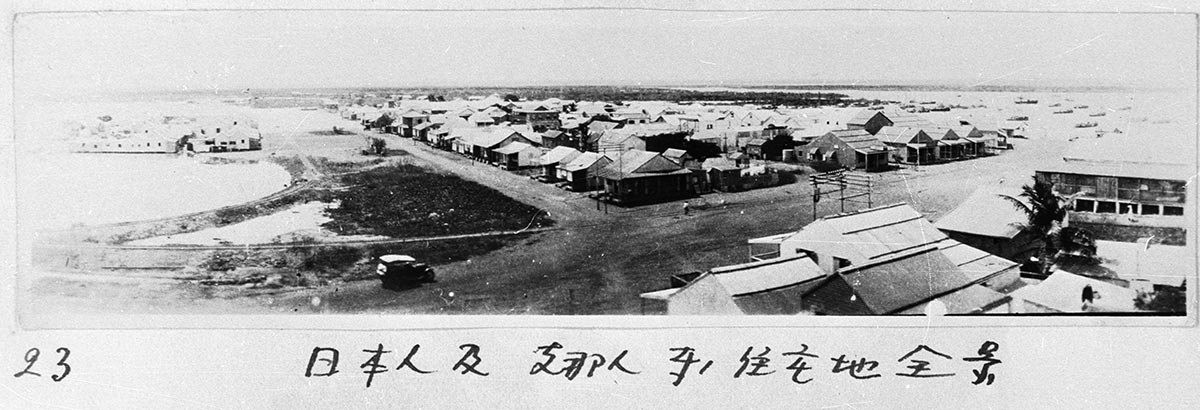 Black-and-white panorama photo of a rural township on a harbour.