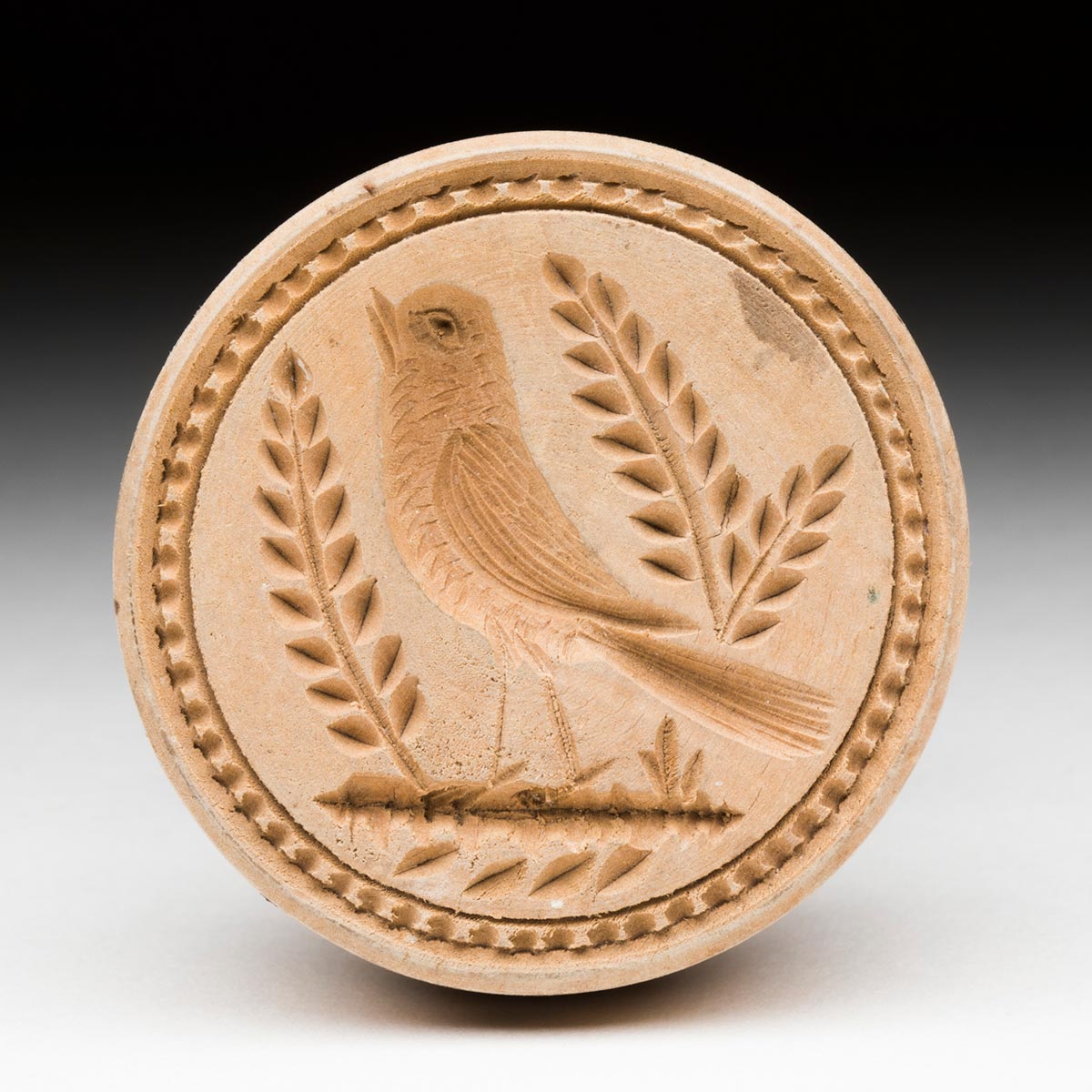 Round shortbread stamp, with wheat bushel pattern of a bird and leaves.