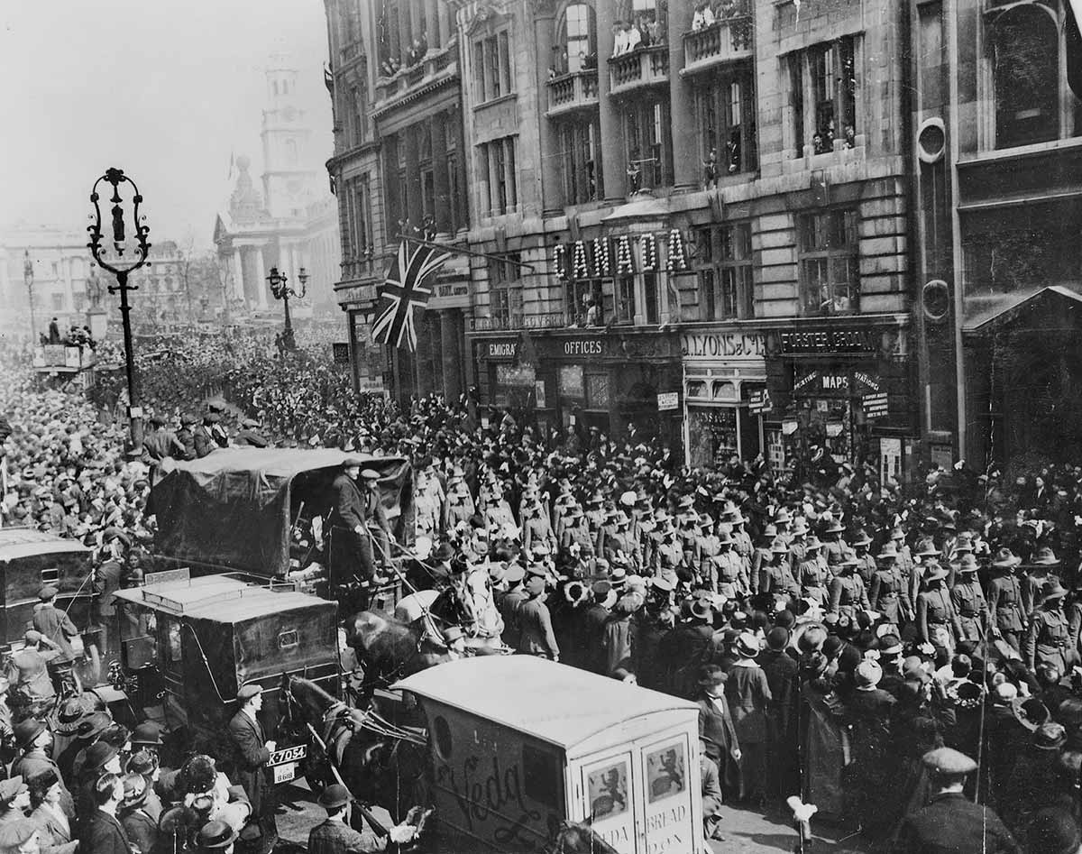 A column of troops marching surrounded on both sides by vast numbers of civilians.