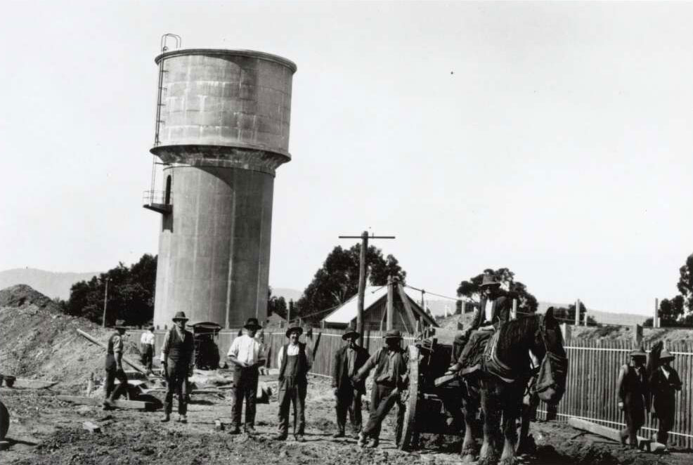 Black and white photograph of a labourers on construction site with a water tower in the background.