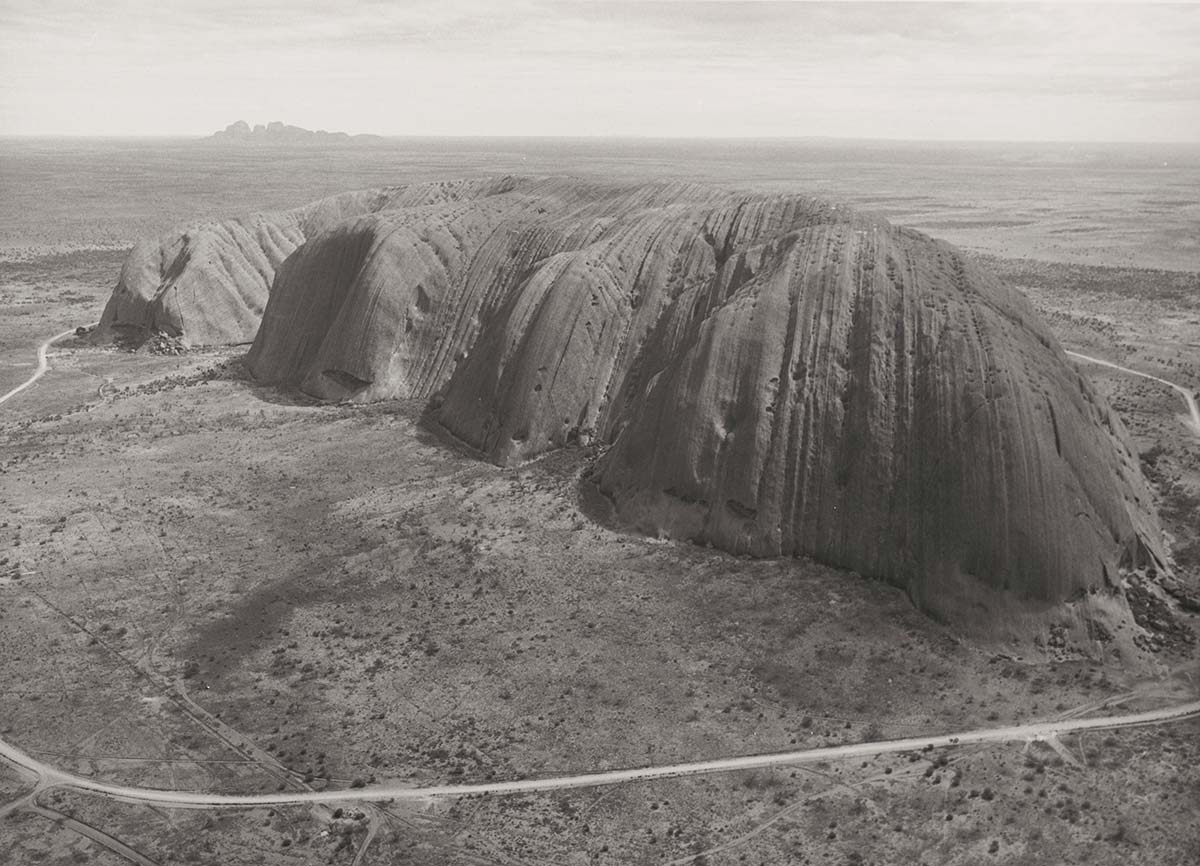 Black and white photo of Uluru and the surrounding National Park.