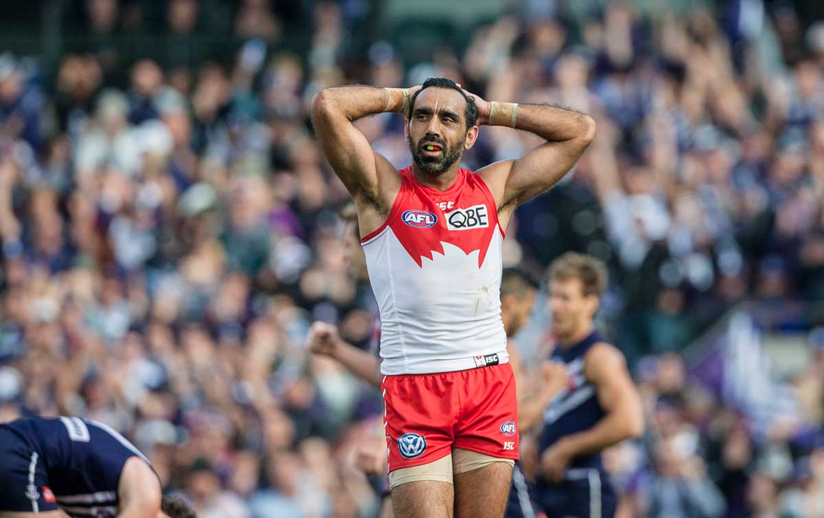 Adam Goodes during a match, standing with his hands rested on the back of his head.