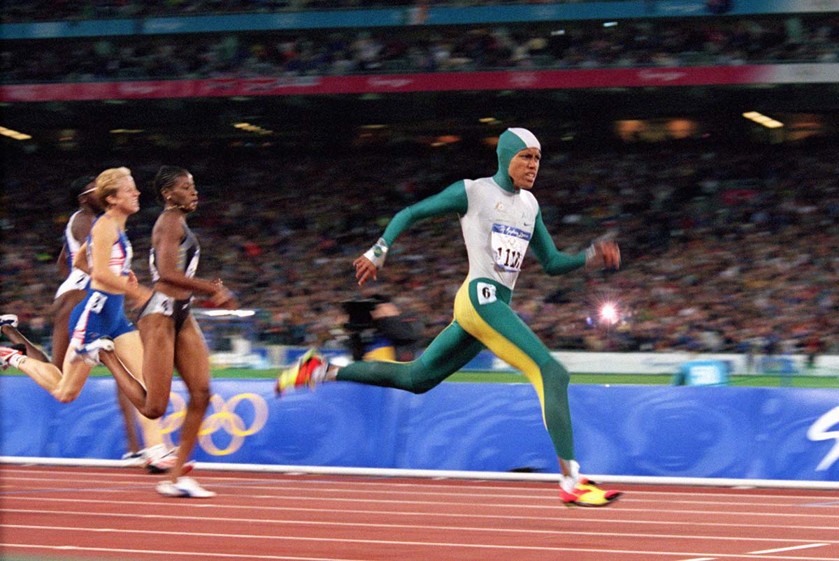Cathy Freeman sprinting ahead of other athletes on a race track.