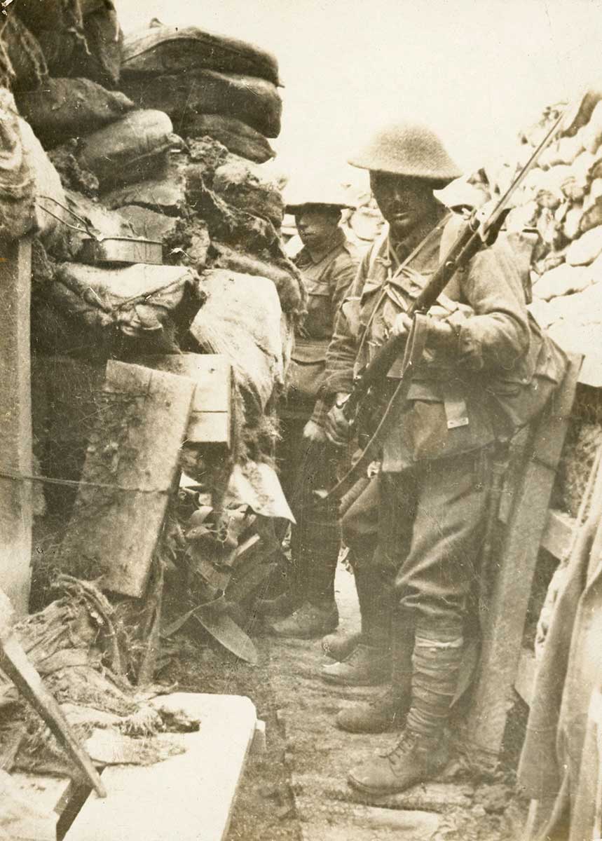 Black and white photograph of Australian soldiers standing ready in a trench on battlefields.