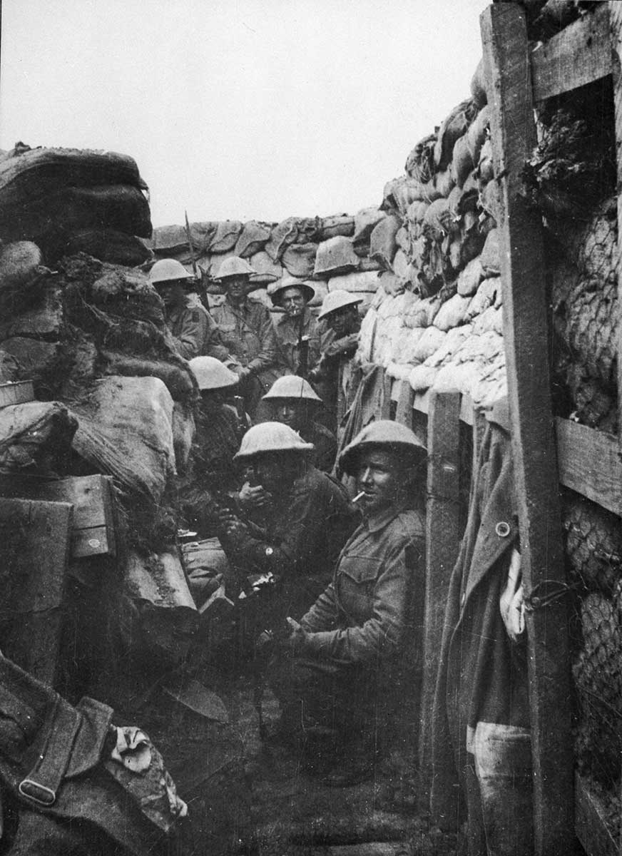 Black and white photograph of Australian soldiers sitting or standing in a trench.