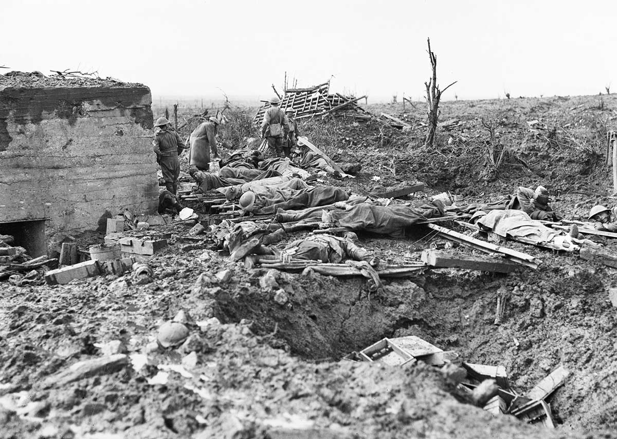 Black and white photograph of Australian soldiers in a muddy battlefield. There are several wounded lying on stretchers, and some possibly deceased.