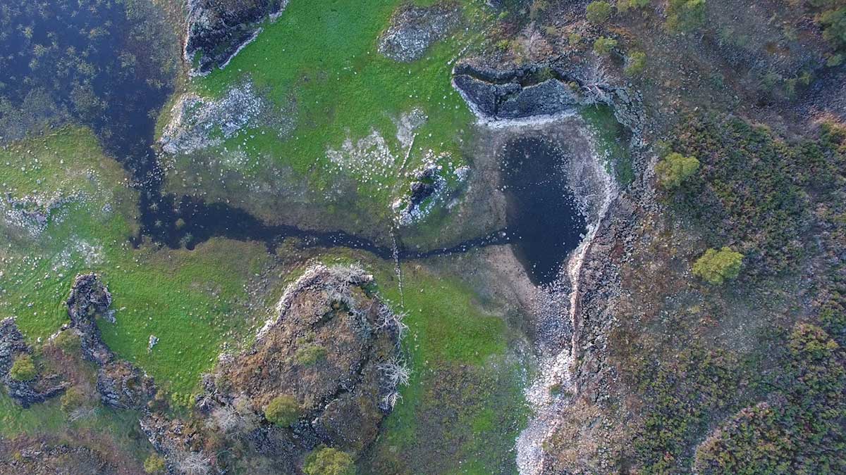 Aerial view of a landscape with a channel of water leading into a smaller body of water.