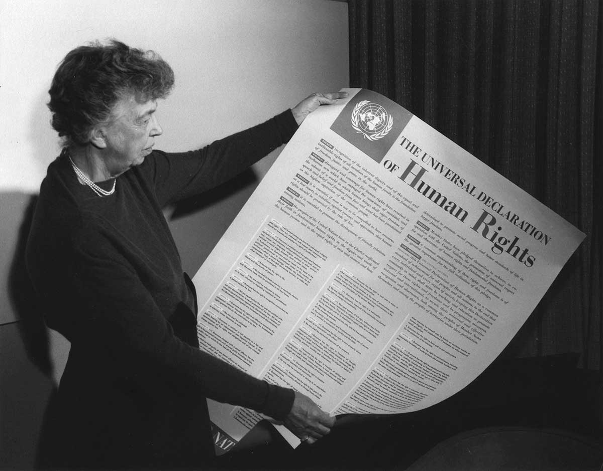 Black and white photo of a woman holding a poster of the Universal Declaration of Human Rights.