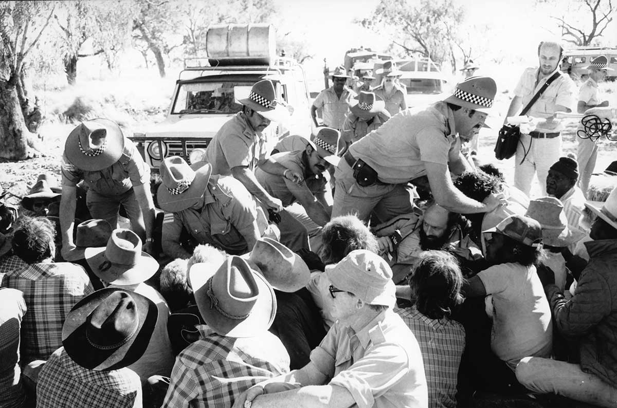 Black and white photograph of police attempting to break up a crowd of rioters.