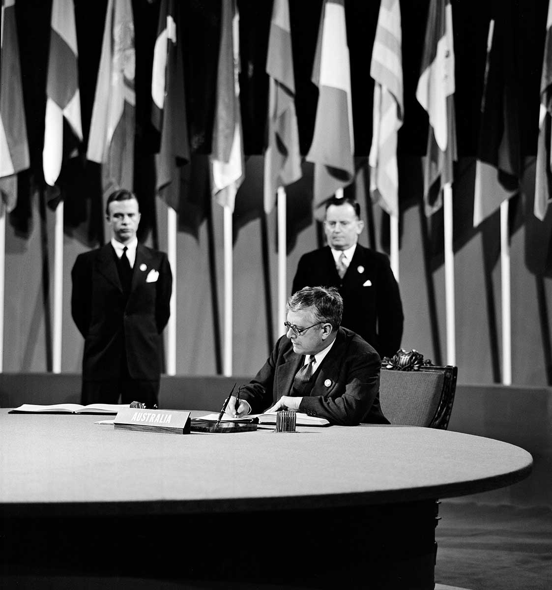 Black and white photograph of Herbert Vere Evatt signing the UN Charter at a ceremony held at the Veterans' War Memorial Building.