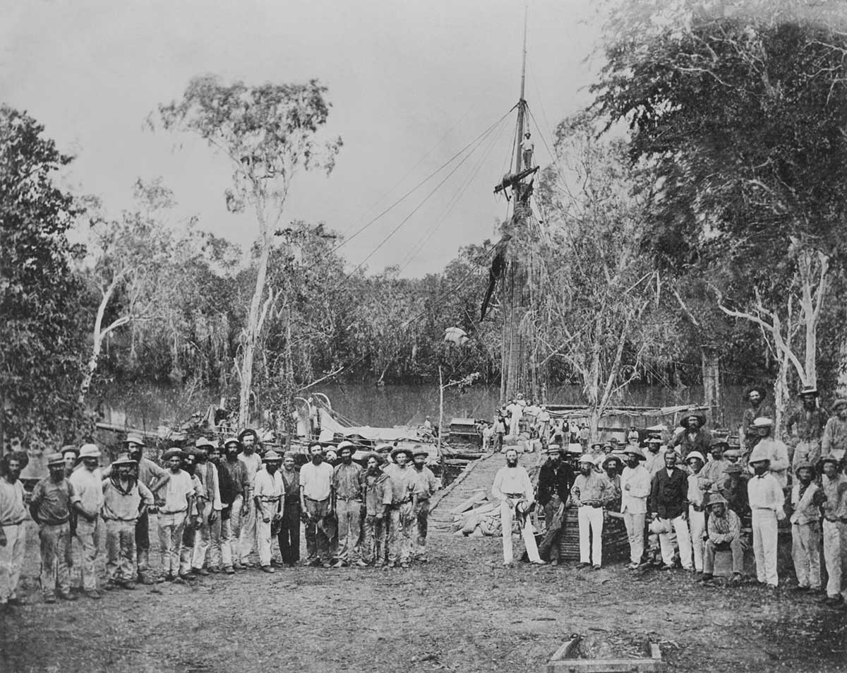 Black and white photograph of a large group of people in front of a telegraph pole under construction.