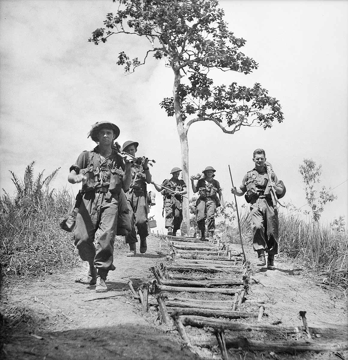 Black and white photograph of a group of soldiers walking down a hill on either side of a makeshift staircase.