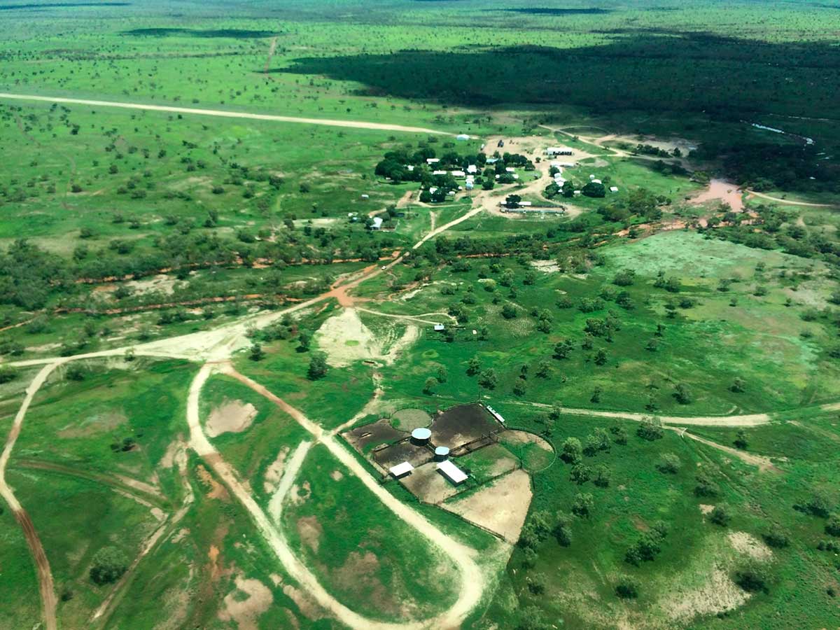 Colour photograph of an aerial view of a farm station surrounded by lush green landscape.