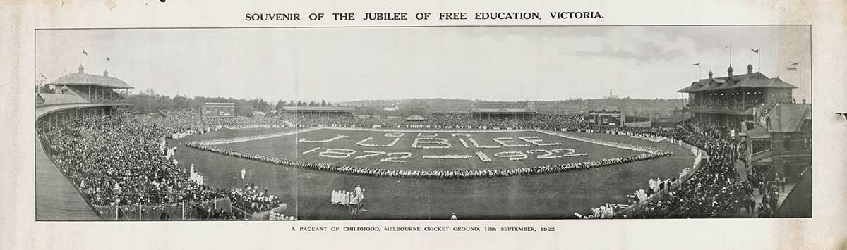 Black-and-white panorama photograph of the Melbourne Cricket Ground filled with crowds watching from the sidelines. People have gathered on the oval to form a huge rectangular border, with more people inside of that forming the text 'OUR JUBILEE 1872–1922'.