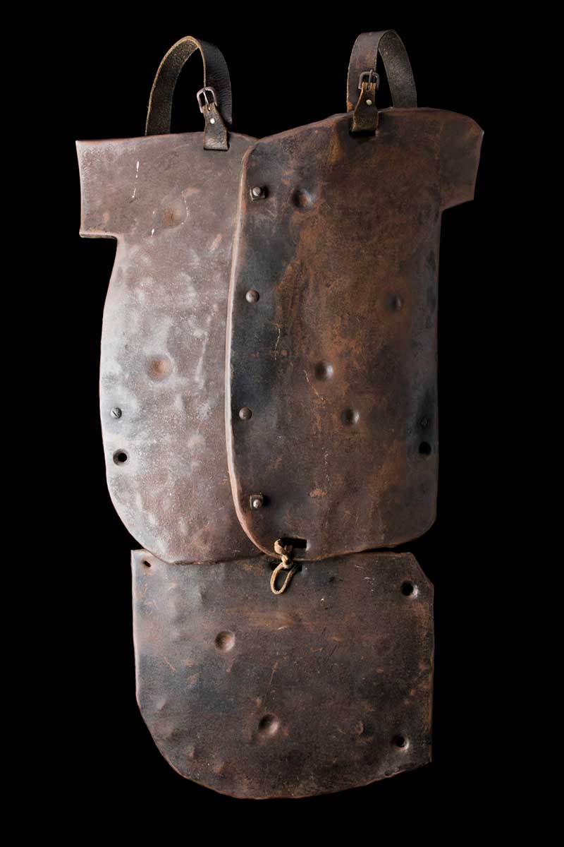 Three piece set of armour composed of breastplate, groin plate with leather straps. It has a rusty weathered steel finish.