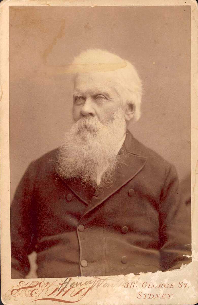 Studio photographic portrait of older man, with white hair and long white beard.