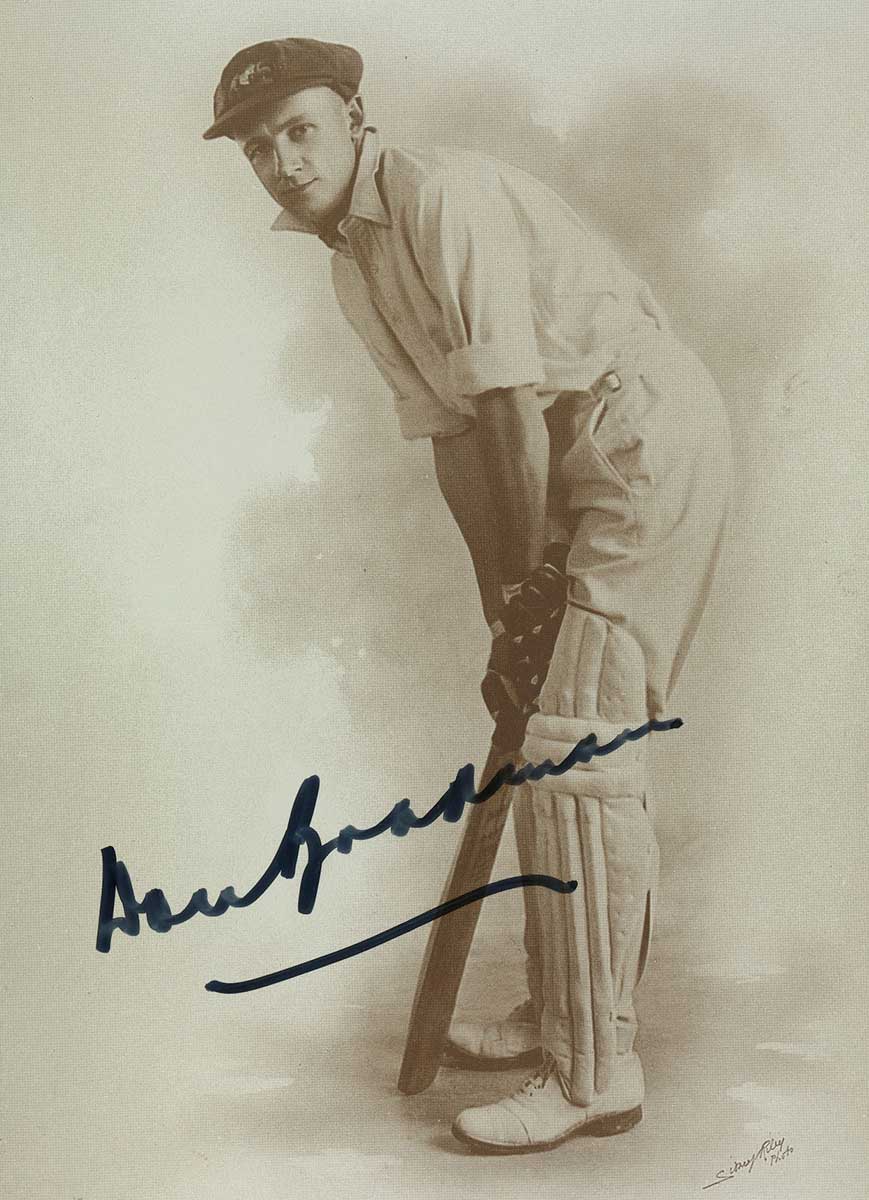 Autographed photo of Don Bradman posing with cricket bat in 1928.