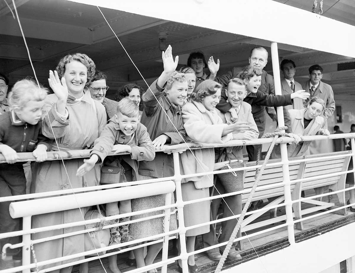 Black and white photograph of people waving off the side of a ship.
