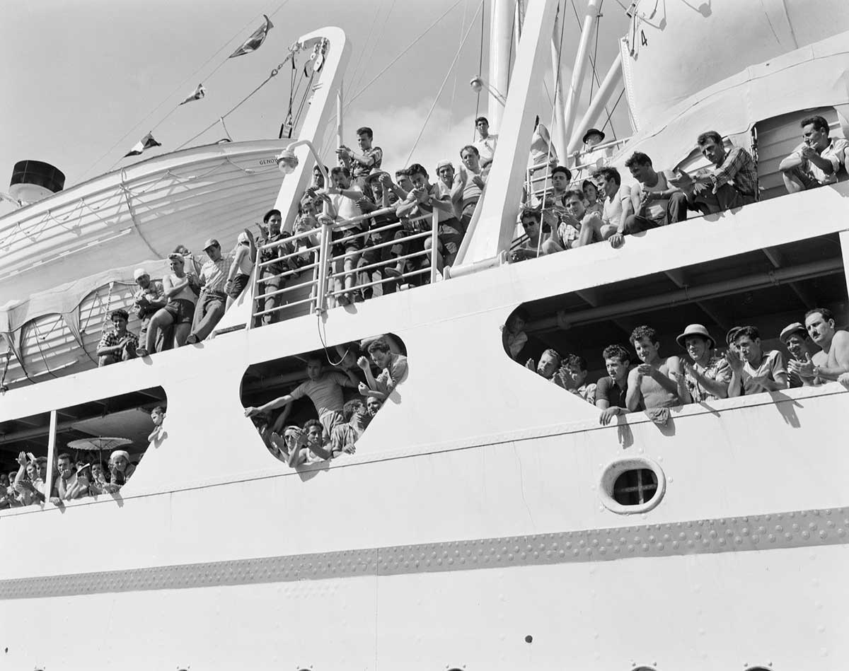 Black and white photograph of people watching off the sides of an ocean liner.