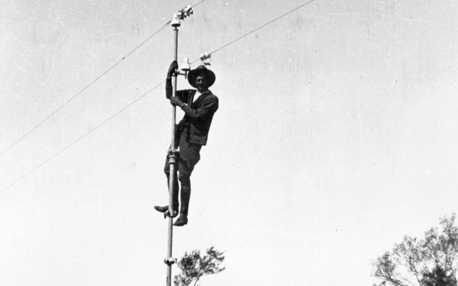 Bob Carew up a pole of the Overland Telegraph line.